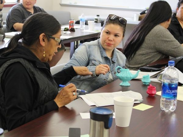 tow women sit at a table in discussion