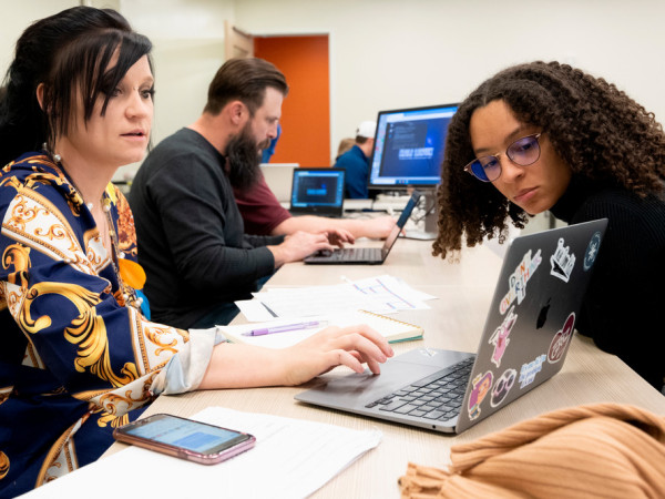 Two individuals sitting at a laptop to see if one qualifies for cpl or not.