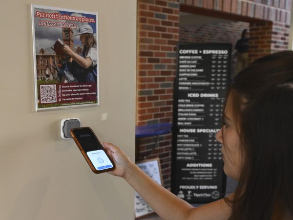 A female student taps her phone to a Brick device in the College of Education.