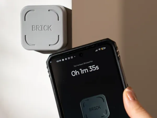 Brick device (mounted on wall) appears next to iPhone. On the iPhone screen, the Brick app shows that the phone has been 'bricked for 1m 35s.'