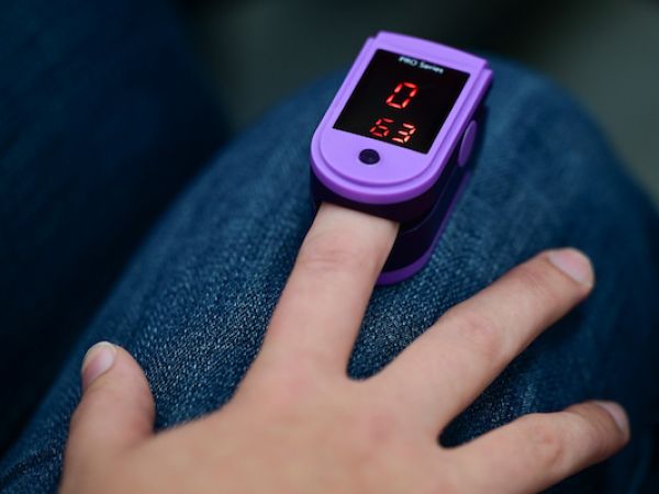 Someone measuring their oxygen levels using a device on the end of their finger
