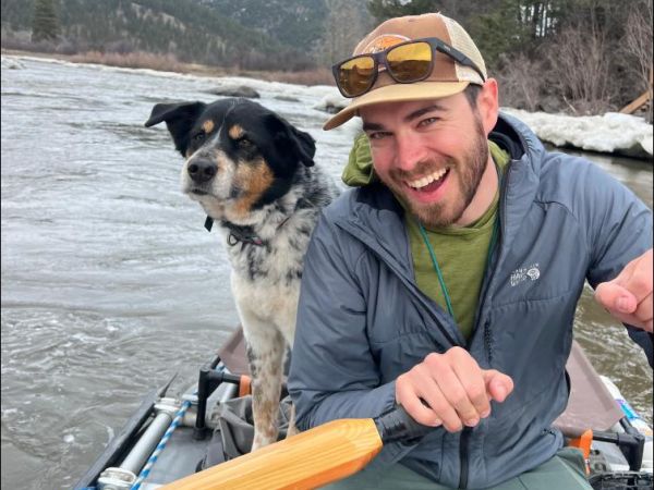 Zach Hoylman rowing on a boat on a river with his dog
