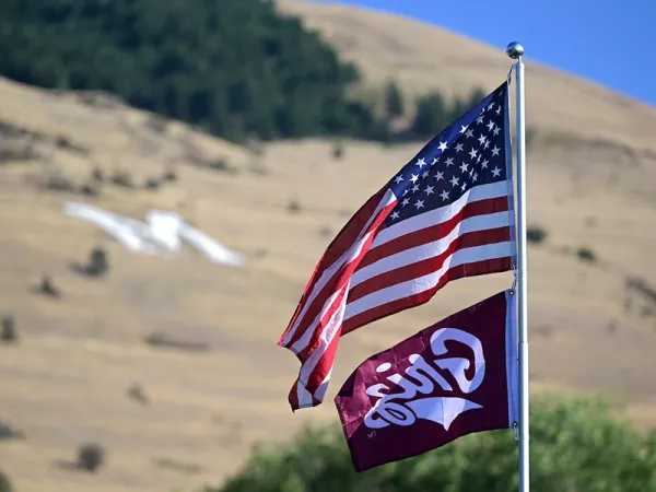 An American flag and a Griz flag fly with the M on Mount Sentinel in the background