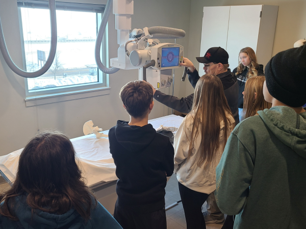 A role model demonstrates how to use an X-ray machine to a group of middle school students.