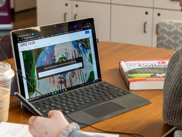 Student taking notes while working on laptop
