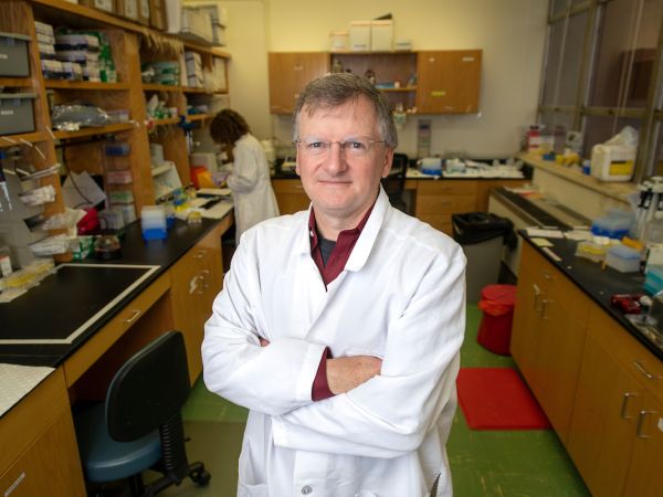 Jay Evans stands in a white lab coat in a lab 