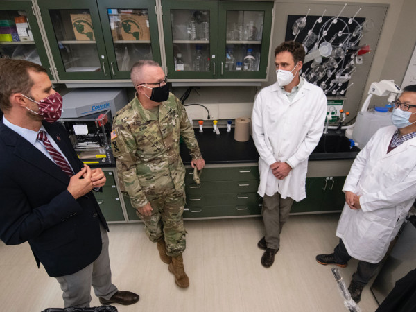 Four government officials speak in a UM lab.