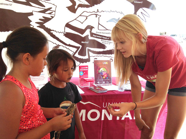 A spectrUM educator shares wildlife specimens with young visitors to the Science Learning Tent at the Arlee Celebration.