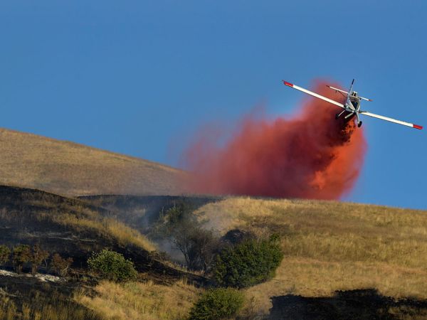 A plane dumps retardant on a fire burning on Mount Sentinel near the UM campus.