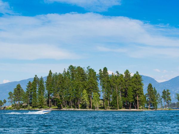 A boat drives by an island on the waters of Flathead Lake.
