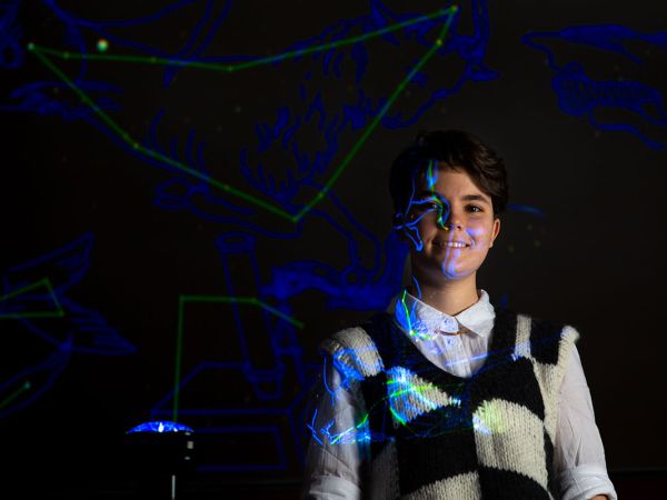 A picture of Ailey Robinson illuminated by projected light in the planetarium of UM's Payne Family Native American Center.