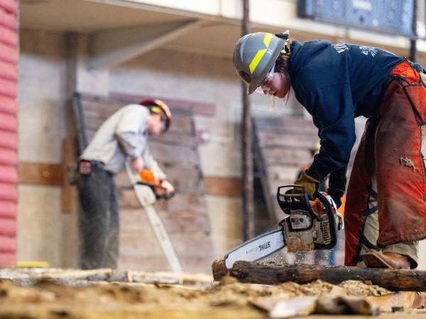 A photo of a forestry student using a chainsaw to build the Foresters' Ball.