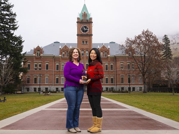 UM faculty members Anisa Goforth (left) and Jingjing Sun hold the 2024 Public Impact Research Award.