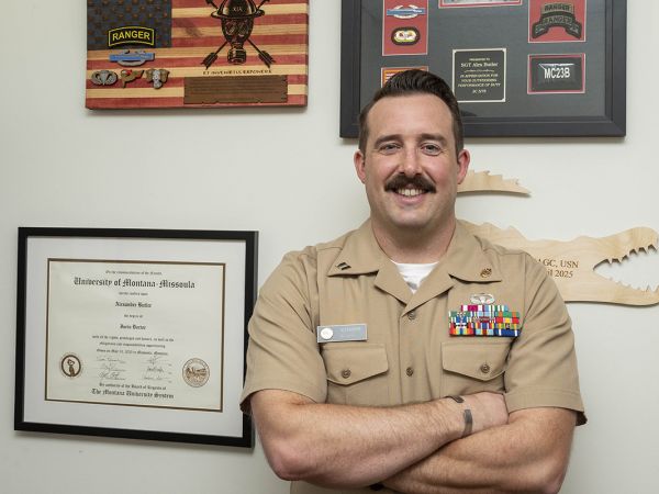 UM graduate Alex Butler poses with his diploma while wearing his military uniform