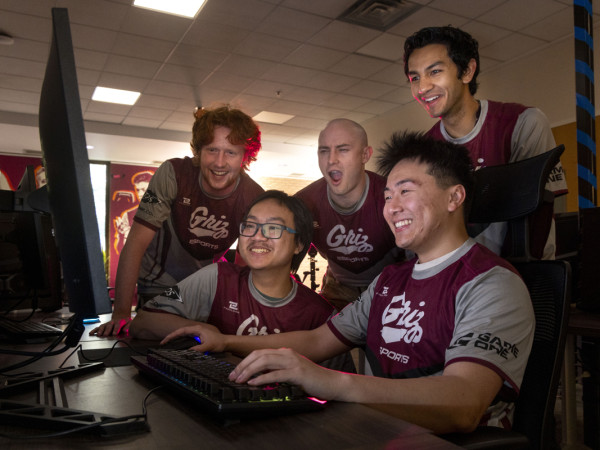 Memebers of the University of Montana Esports team surround one of their fellow teammates who is playing a computer-based video game.