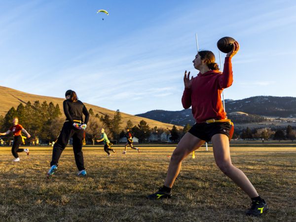 Flag football players practice throwing and catching.