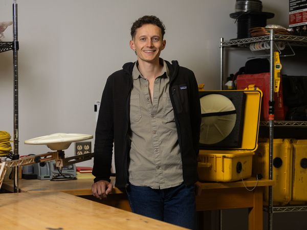 A picture of Matthew Swarr with some science equipment behind him.