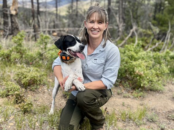 A picture of Nicole Tatman in a forest with a dog.