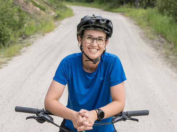 A picture of Abigail Fuesler on a mountain bike on a gravel road in high country.