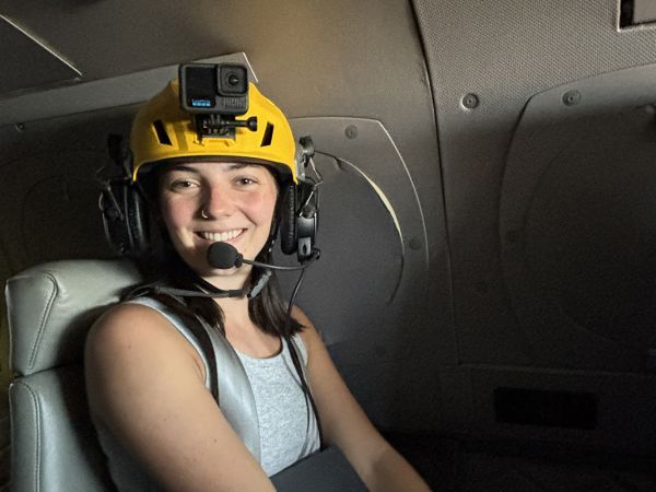 A picture of Amity Deters wearing a helmet inside the research plane.