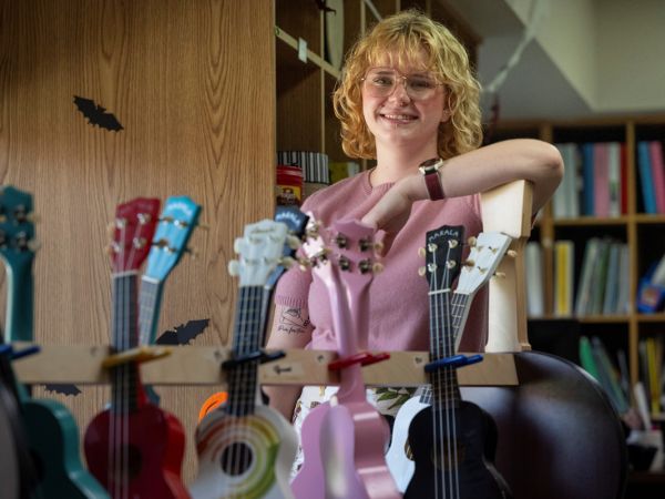 An image of Emma McMillan in her classroom surrounded by musical instruments. 