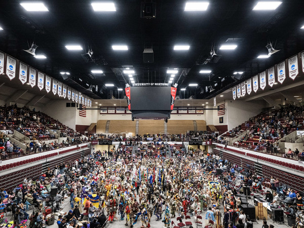 Indigenous dancers fill the floor of the Adams Center for the powwow