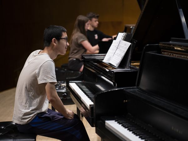 A piano player sits in front of a piano 