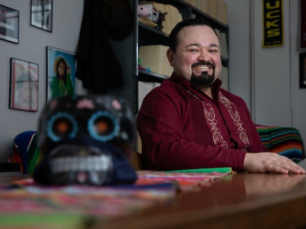 A man sits at a desk and smiles 