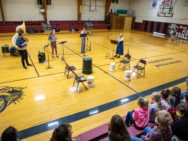 UM music alumni play instruments in a school gymnasium 