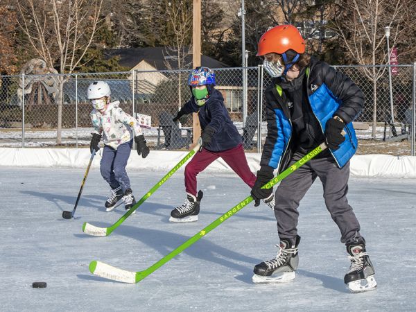Three children skate on the ice rink on the UM Oval. 