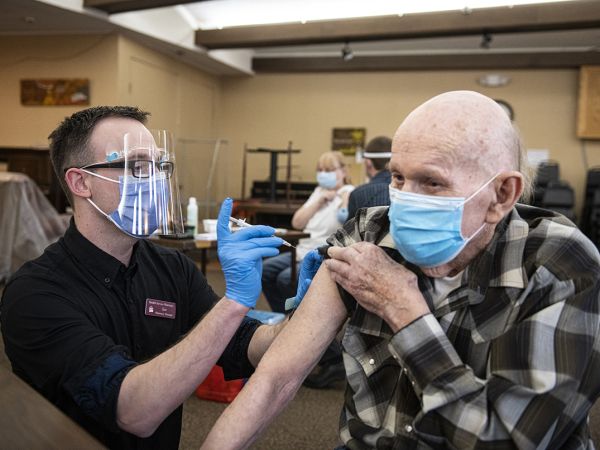 A UM pharmacist vaccinating an elderly man.  