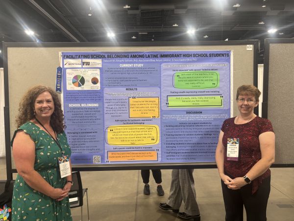 A graduate student and a professor standing in front of a conference poster
