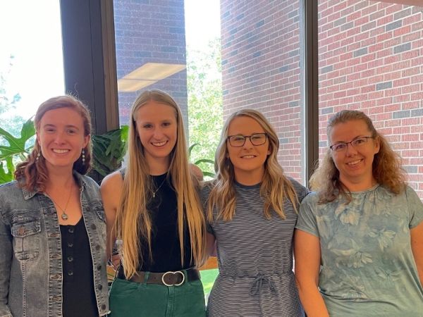 four school psychology PhD students smiling in the Skaggs building