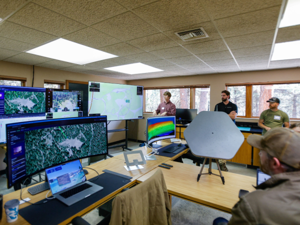 Group standing around a technology presentation in Lubrecht facilities