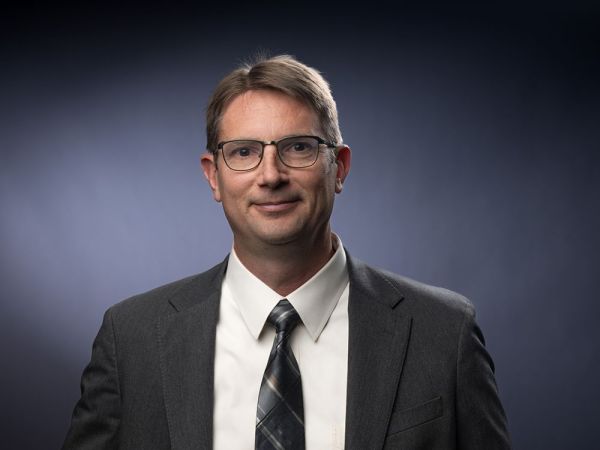 Paul Lukacs smiling for the camera in a suit
