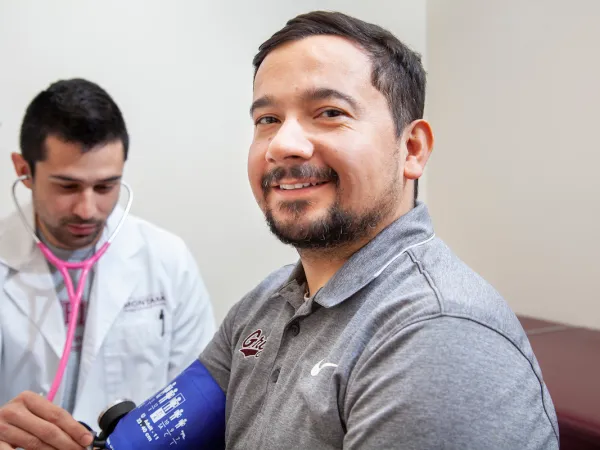 A University of Montana pharmacy student is taking the blood pressure of a UM student.