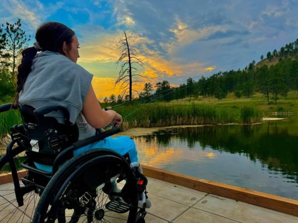 Woman who uses a wheelchair fishing on a dock
