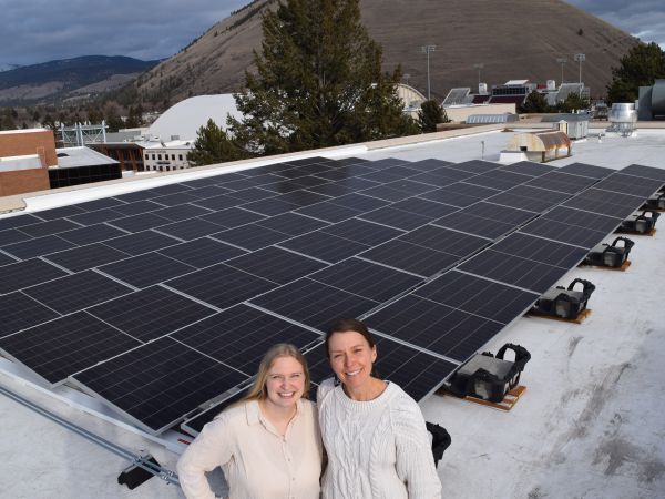 Two women stand in front of Education Building Solar Array 