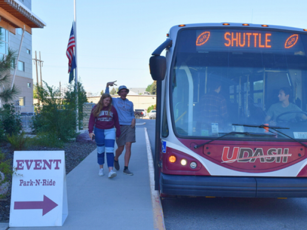 two people pose as they are getting on the football shuttle at Missoula College