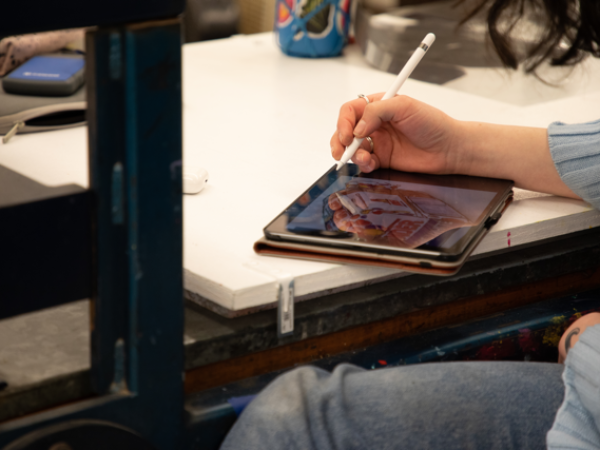 An iPad and stylus on a table, with a design on the screen