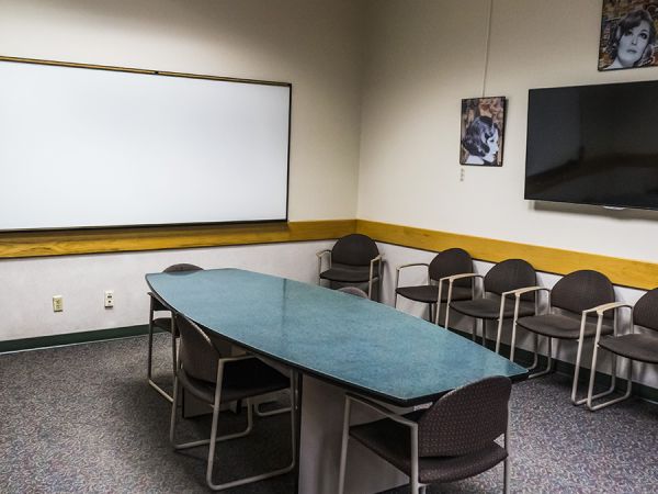 Green table in an empty room surrounded by chairs 