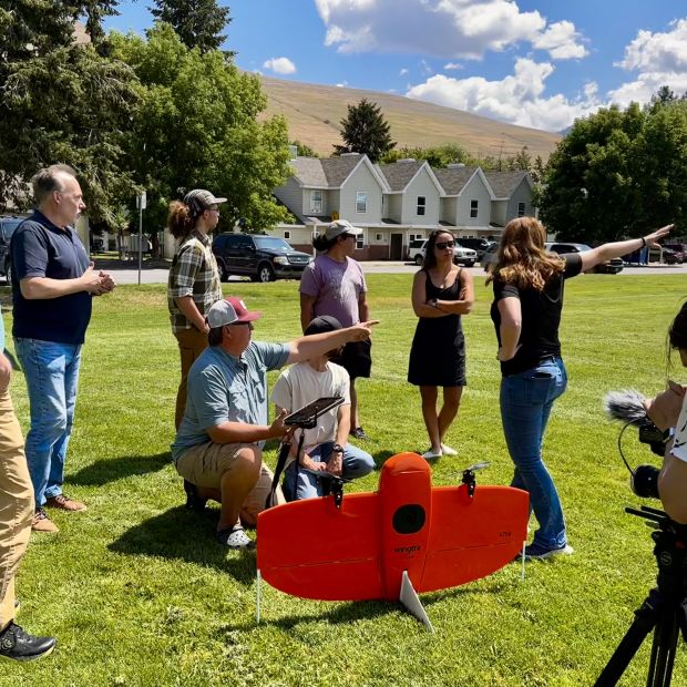 group of people on a lawn gathered around a drone