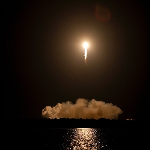 An image of a missile launching above water at night