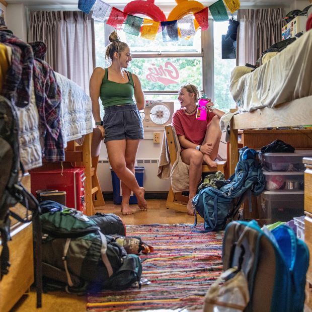 two girls smiling inside their newly-furnished dorm room