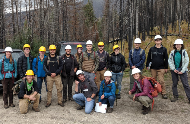 Class of students poses outside wearing hard hats