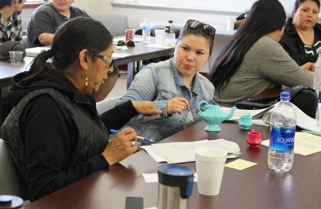 tow women sit at a table in discussion