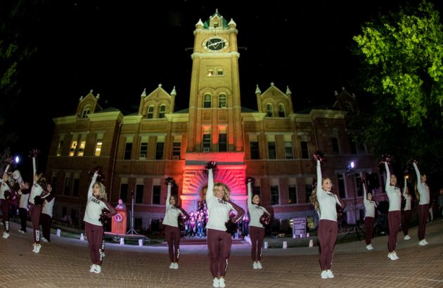 Members of the UM Dance Team perform in front of Main Hall at night during the Homecoming Pep Rally.