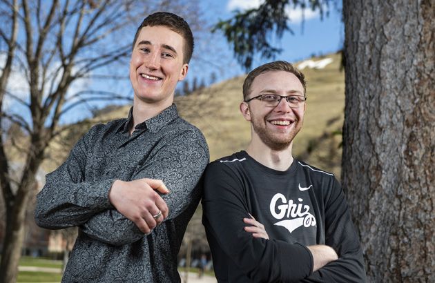 Recent UM graduates Noah Grabe, left, and Taylor Gregory, right, stand back-to-back on campus.