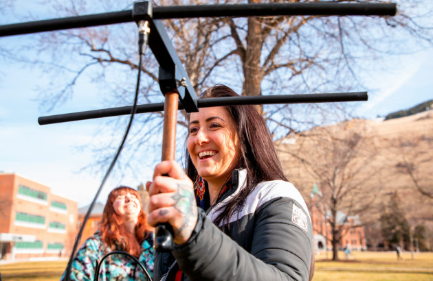 A woman smiles and holds a piece of equipment