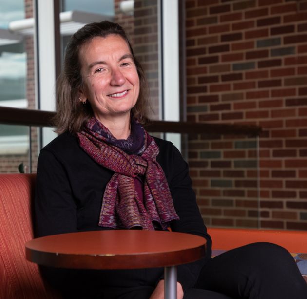 Sofia Reis sits in a chair in the Education Building at UM and smiles at the camera